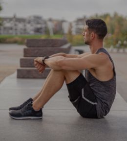 Image of a man sitting down an outdoor exercise area.