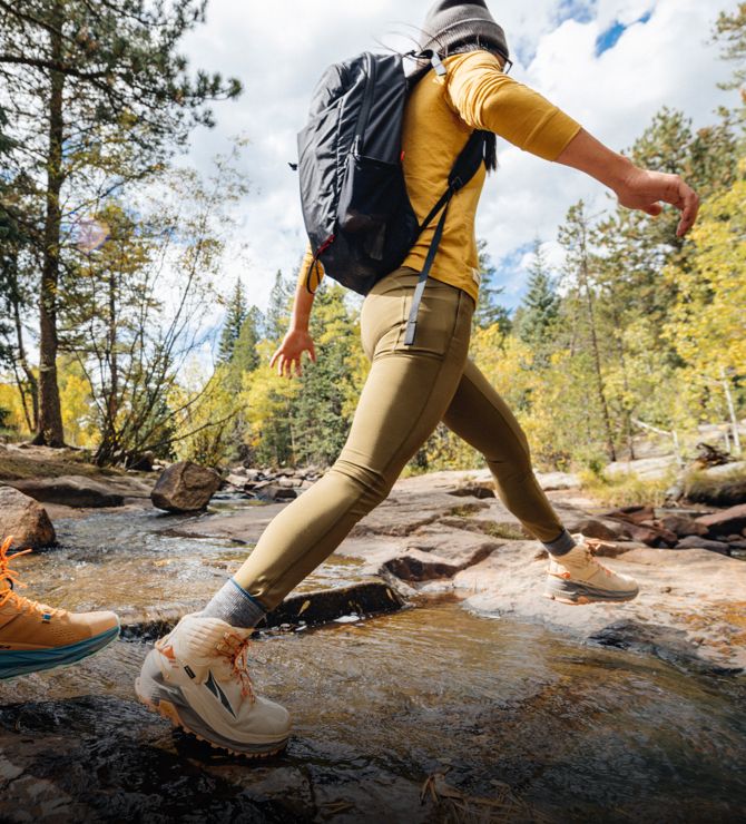 Image of a person crossing a stream with a backpack.